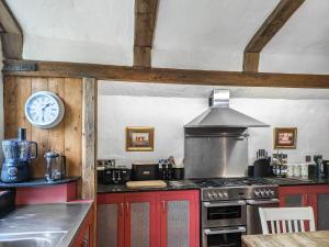a kitchen with a stove and a clock on the wall at Stable End in Halesworth