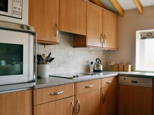 a kitchen with wooden cabinets and a microwave at Magpie Cottage in Gristhorpe
