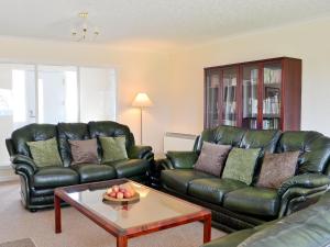 a living room with leather couches and a coffee table at Tall Pines in Carrbridge