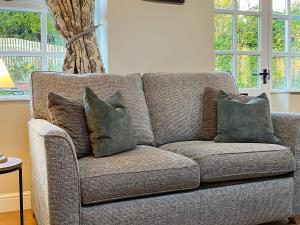 a couch with three pillows on it in a living room at The Farriers - 26967 in Windermere