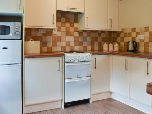 a kitchen with white appliances and white cabinets at The Farriers - 26967 in Windermere +8 photos