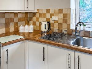 a kitchen with white cabinets and a sink at The Farriers - 26967 in Windermere