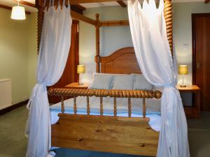 a bedroom with a wooden bed with curtains at Jasmine Cottage - E1493 in Scalby +6 photos