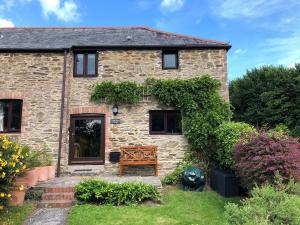 a stone house with a wooden bench in the yard at Cider Press Cottage in Fowey