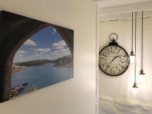 a clock hanging on a wall next to a painting at Cider Press Cottage in Fowey +21 photos