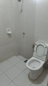 a white bathroom with a toilet and a tiled floor at QMR Homestay in Kampong Jelatang
