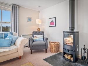 a living room with a wood stove and a chair at Ash Tree Cottage in Bosherston