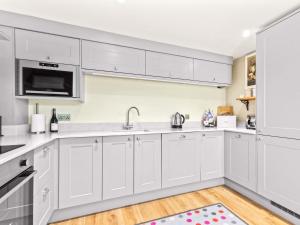 a kitchen with white cabinets and a sink at Ash Tree Cottage in Bosherston +28 photos