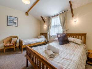 a bedroom with two beds and a chair at Spinnaker - 16828 in Staithes