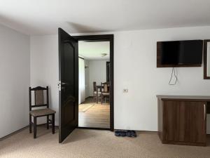 a room with an open door with a chair and a television at Casa din Codru in Şimon