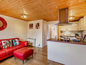 Una sala de estar con un sofá rojo y una cocina. en Strawberries And Cream, en Bowness-on-Windermere