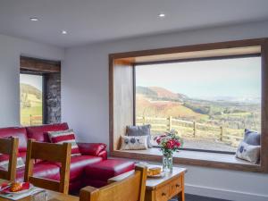 a living room with a red couch and a large window at Pistyll Gwyn in Llanwrthwl