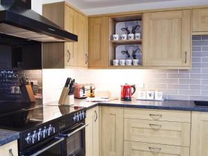 a kitchen with wooden cabinets and a stove top oven at Pistyll Gwyn in Llanwrthwl