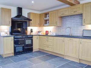 a large kitchen with wooden cabinets and black appliances at Pistyll Gwyn in Llanwrthwl
