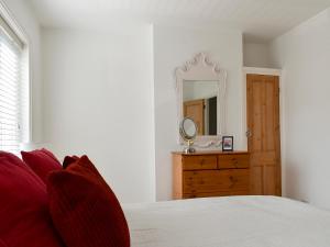 a bedroom with a bed with a mirror and a dresser at Shingle Cottage in Whitstable