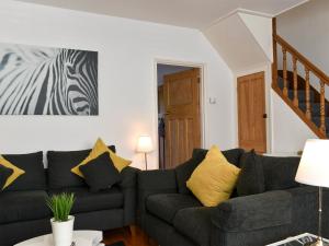 a living room with a black couch with yellow pillows at Shingle Cottage in Whitstable +8 photos