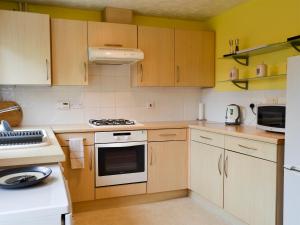 Una cocina con electrodomésticos blancos y gabinetes de madera. en Marina View, en East Cowes