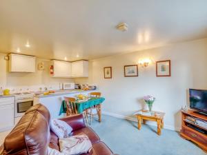 a living room with a couch and a kitchen at Blossom Cottage in Goldsborough
