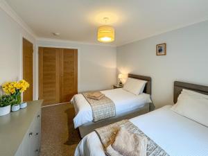 Un dormitorio con dos camas y una mesa con flores. en Lower Moon, en Port Isaac