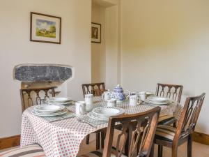 a dining room table with plates and cups and chairs at Yew Tree Cottage in Windermere
