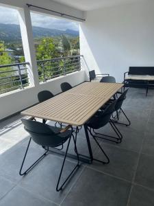 a wooden table and chairs on a balcony at Le meublé du Sable Nwar in Étang-Salé