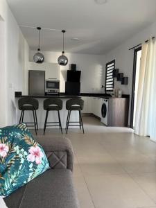 a living room with a couch and a kitchen at Le meublé du Sable Nwar in Étang-Salé