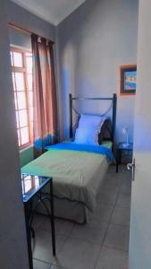 a bedroom with a bed and a table and a window at 27 Pendleberry Grove, Chris Hani Drive, Bela-Bela in Bela-Bela