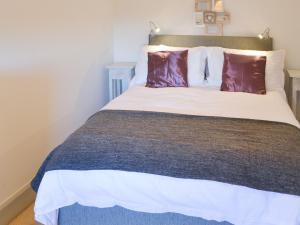 a bedroom with a large bed with purple pillows at Beachcomber Cottage in Woodhorn +9 photos