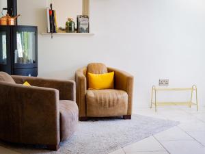 ein Wohnzimmer mit 2 Stühlen und einem gelben Kissen in der Unterkunft Mallard Cottage in Winchester