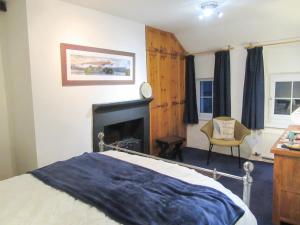 a bedroom with a bed with a fireplace and a chair at Garden Cottage in Threlkeld +7 photos