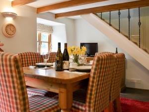 a dining room with a table with wine bottles and chairs at Pineview Cottage in Downderry