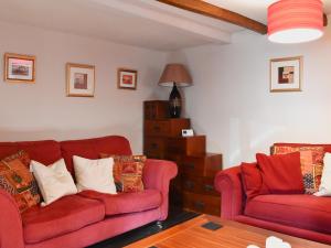 a living room with two red couches and a table at Pineview Cottage in Downderry