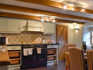 a kitchen with a black stove top oven next to a table at Pineview Cottage in Downderry +6 photos