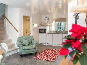a living room with a chair and a kitchen at Cranford-Cottage in Saint Brides +18 photos