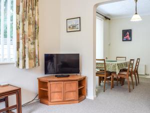 una sala de estar con un televisor y una mesa en Mona's Bungalow, en Wellesbourne