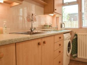 una cocina con fregadero y lavadora en Mona's Bungalow, en Wellesbourne 14 fotos más