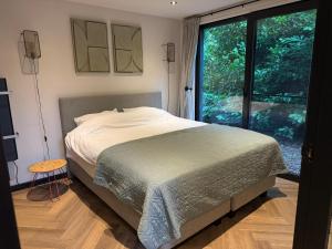 a bedroom with a bed and a large window at Fantastisch luxe boshuis I Onthaasten in de natuur in Emst +20 photos