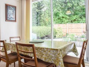 Un comedor con mesa y sillas y una ventana. en Mona's Bungalow, en Wellesbourne