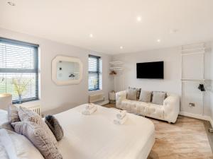 a white living room with a couch and a tv at North Plain Barn in Bowness-on-Solway +26 photos
