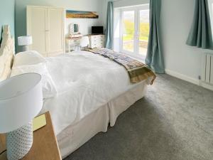 a bedroom with a large white bed and a window at Cae-Fadog Fach in Barmouth