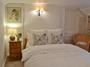ein Schlafzimmer mit einem weißen Bett mit Kissen und einer Lampe in der Unterkunft The Thatch Cottage in South Petherwin