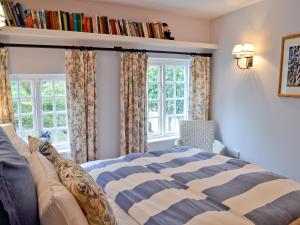 ein Schlafzimmer mit einem Bett und einem Bücherregal mit Büchern in der Unterkunft The Thatch Cottage in South Petherwin