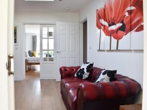 a living room with a red leather couch at Keepsake View in Two Dales
