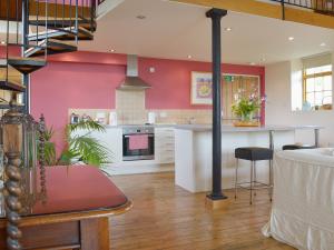 a kitchen with pink walls and a kitchen with a table at Little Burcott Loft in Wookey