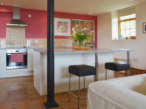 a kitchen with a counter and stools in a room at Little Burcott Loft in Wookey