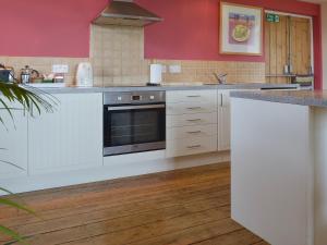 a kitchen with white cabinets and a stove top oven at Little Burcott Loft in Wookey +5 photos