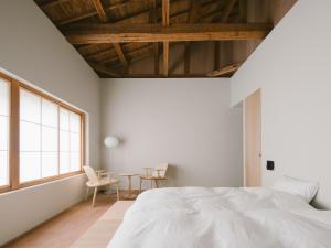 a bedroom with a white bed and a table and chairs at YALDA apartment in Kanazawa
