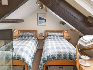 two twin beds in a attic bedroom with a tv at Seascape Cottage in Allonby