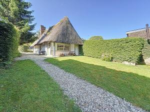 a house with a thatched roof and a gravel driveway at la chaumière de Vieux Port in Vieux-Port