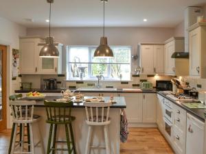 a kitchen with white cabinets and a island with bar stools at Quarryman's Cottage in Belford